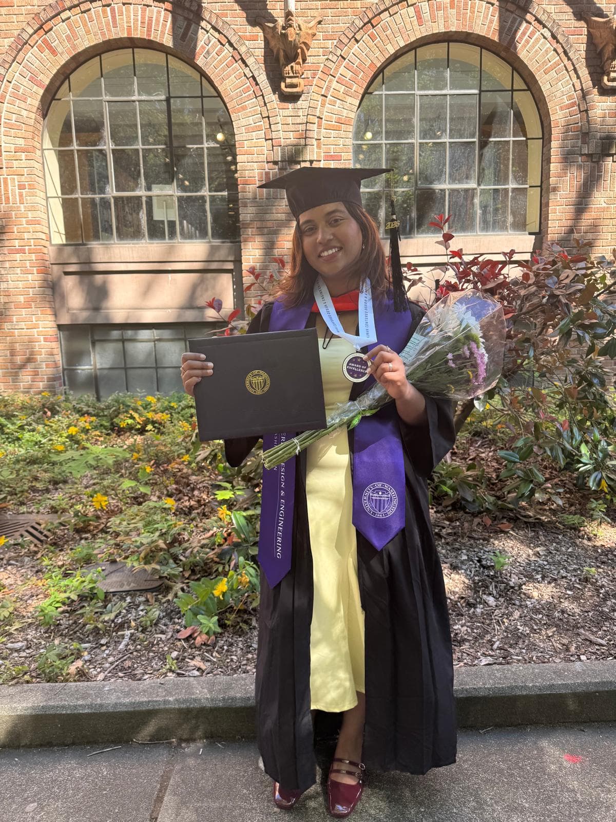 Reshma holding her diploma at graduation